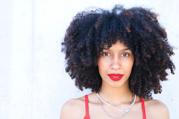 beautiful afro american woman smiling and looking at the camera doing different poses and gestures with her face. The woman is wearing a red top and red lipstick. Concept happiness