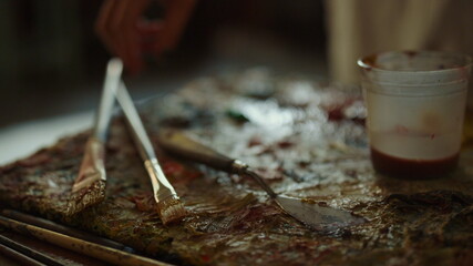 Unknown woman hand choosing tools indoors. Female painter taking paintbrush.