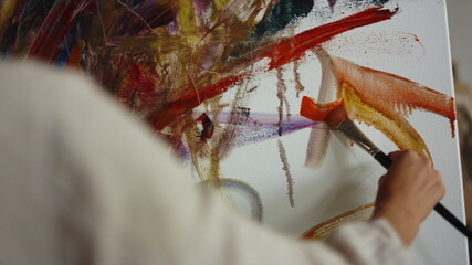 Unknown painter making brush stroke indoors. Female artist working in studio.
