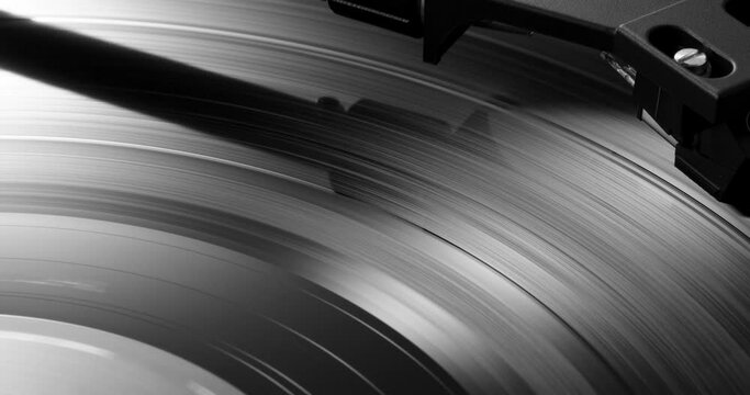 Extreme closeup of turntable's tonearm headshell on spinning vinyl record 