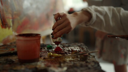 Unknown woman mixing colors on palette. Students working in art studio.