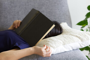 ソファで読書しながら寝落ちした女性
