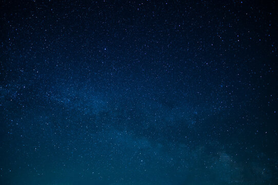 In the photo we see the Milky Way, the night sky. All shades of blue. Twinkling stars. Wallpaper. Texture. Background. High angle view. Place for your inscription.