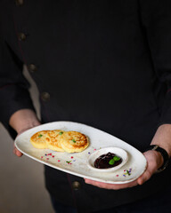 the waiter serves a tray of products with Belarusian cheese cakes