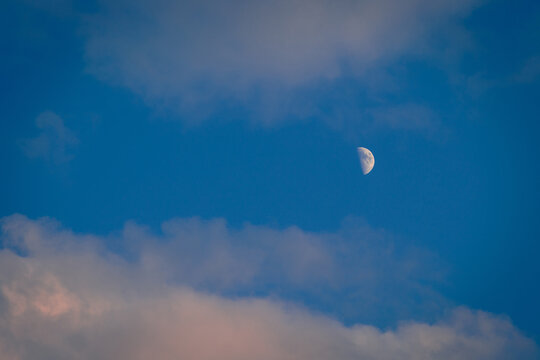 Half moon on a blue sky with clouds background. - Powered by Adobe