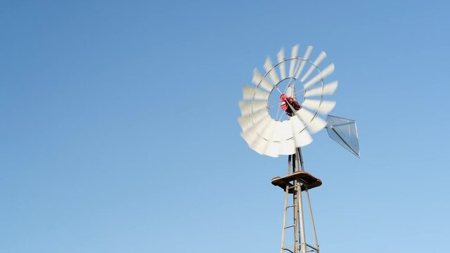 windmill pumping water for cattle against blue sky, Pawnee National Grassland in Colorado