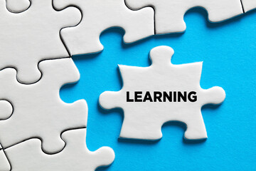 Fototapeta premium The word learning on a puzzle piece with blue background. Education concept.