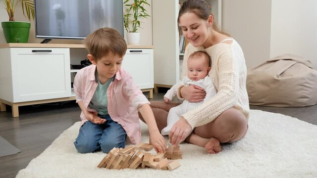 Happy mother with her little sons playing games on floor in living room. Parenting, children happiness and family relationship