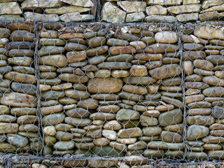 The texture of the gabion. Background of gray stones in a steel grid. A pile of cobblestones to strengthen the mountains, a detailed close-up photo.