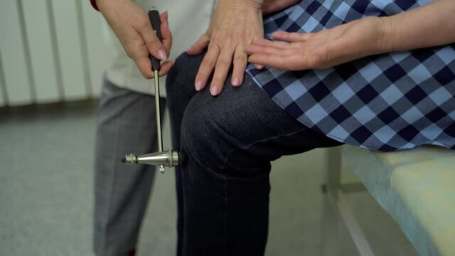 Doctor examining the knee reflex. Close up of neurologist checks reflex of patient