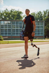 Fototapeta premium Full length of male athlete with artificial leg comes to practice at the stadium.