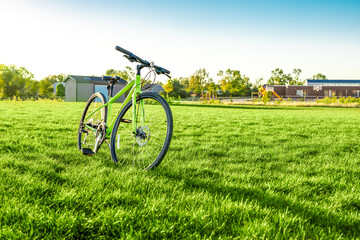 Bicycle parking at green field with blurred background of public school buildings and playground under sunny clear sky, idyllic nature outdoor. Relaxation activity in summer weekend, rural lifestyle. - Powered by Adobe