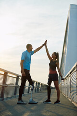 Happy athletic man and woman with disability giving high five to each other after successful...