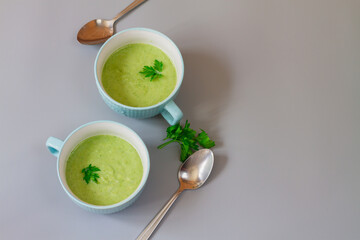 Green cabbage broccoli soup in plates decorated with parsley leaves