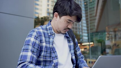 slow motion scene young middle eastern man sit at outdoor public park and use laptop to type task or search information on website alone for freelance work lifestyle concept