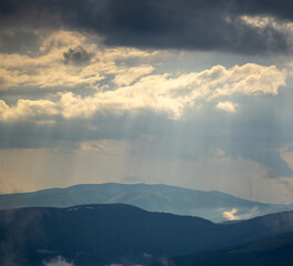 Naklejka na ściany i meble The sun's rays shine through the clouds over the Carpathian mountains