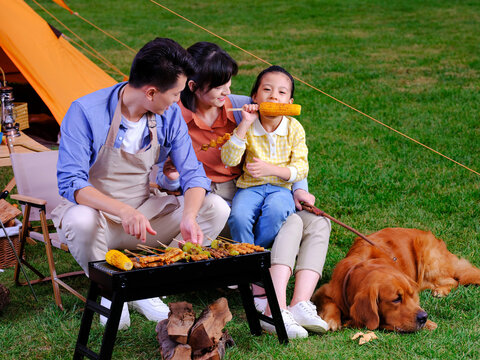 Happy family of three and pet dog barbecue in the park