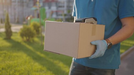 Delivery Hand of young man pays for purchases using the contactless payment nfs system. Young delivery man hold package man client paying by phone for parcel transporting payment uniform express order