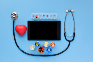 Prescription medication with doctor's stethoscope, red heart and wireless tablet on blue background