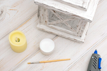 Fototapeta na wymiar Decorative carton lantern with a piece of cardboard, glue gun and hot glue on a white wooden table.
