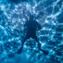 Underwater selfie, silhouette against sandy bottom with sunlight in the back of the diver, in Maldives