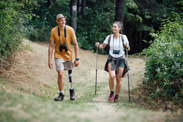 Young happy woman and her boyfriend with prosthetic leg hiking through nature.