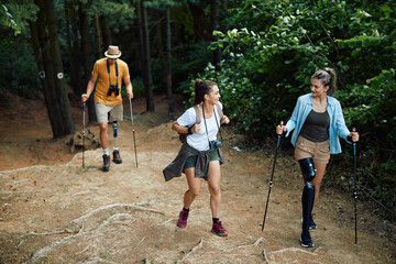 Young happy friends talking while hiking in the woods. Two of them are with disability and have prosthetic legs.