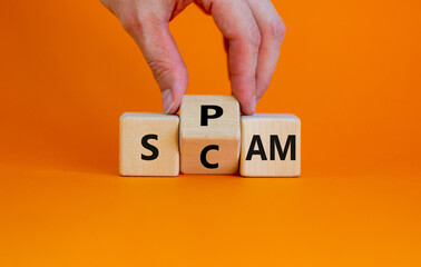 Spam and scam symbol. Businessman turns the wooden cube and changes the word 'scam' to 'spam' or vice versa. Beautiful orange background, copy space. Business, spam and scam concept.