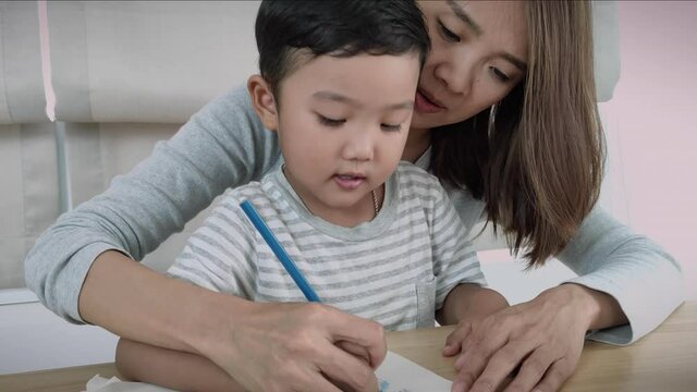 Mother teaches her son to do homework and draw pictures together