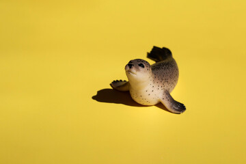 Cute toy fur seal on a bright yellow background with copy space. Design for fabric, textile, decor.