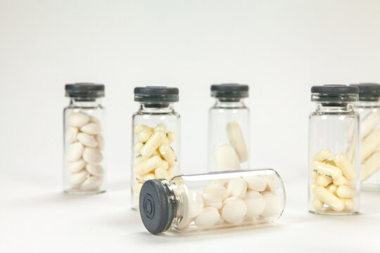 Set of pills on cristal jar for vaccines on coloured background