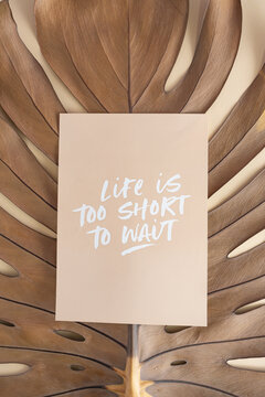 Motivational message: "Life is too short to wait" on a beutiful textured dry leaf of philodendron. Flat lay creative minimal concept.