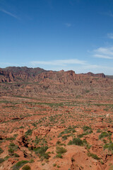 The steep canyon. Panorama view of the red desert, cliffs, orange sandstone formations and rocky mountains in the horizon in Sierra de las Quijadas national park in San Luis, Argentina.