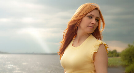 Fototapeta na wymiar Young redhead woman in nature near the river