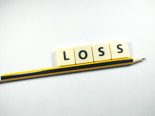 Selective focus.Scrabble letters with text LOSS with pencil on white background.