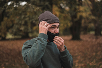 Portrait of a young handsome Caucasian man with mask in a park