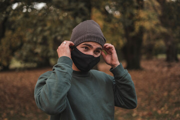 Portrait of a young handsome Caucasian man with mask in a park