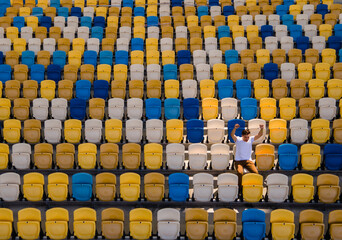 A young man is cheering on an empty tribune of a football stadium