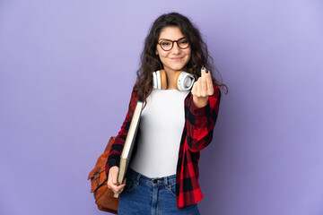 Teenager student isolated on purple background making money gesture