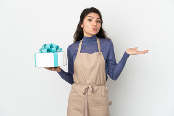 Pastry Russian chef holding a big cake isolated on white background having doubts while raising hands
