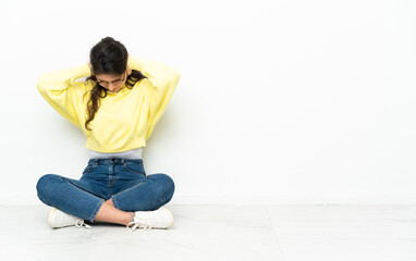 Teenager Russian girl sitting on the floor frustrated and covering ears