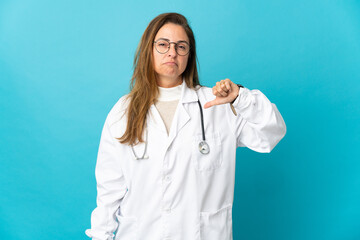 Middle age Brazilian doctor woman isolated on blue background showing thumb down with negative expression