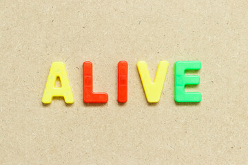 Color alphabet letter with word alive on wood background