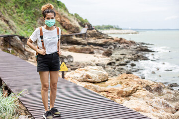 Women wearing a mask walking in nature See the beach and the sea during the coronavirus epidemic situation. New Normal, natural tourism.