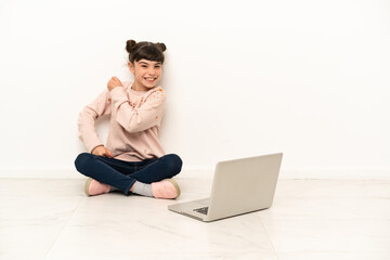 Little girl with a laptop sitting on the floor celebrating a victory