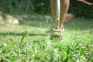 Grass cutting. Man using grass trimmer to mow lawn. Defocused. Machine in motion and grass...