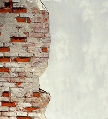 Old cracking plaster wall revealing bricks underneath 