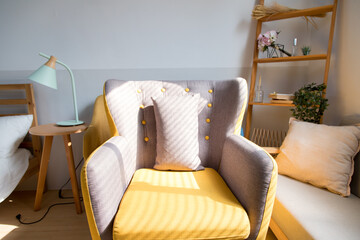 The sun shines on the grey-yellow chair in living room from window.