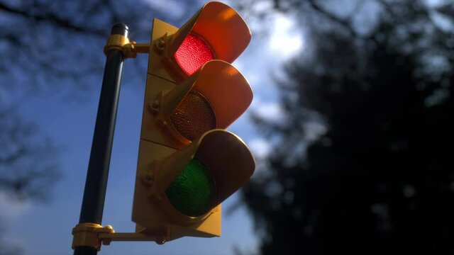 Outdoor vertical traffic light with blue sky and trees around. Traffic control concept image with shallow depth of field.
