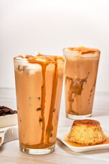 iced caramel macchiato with dripping caramel, accompanied by caramel on a plate and neapolitan...